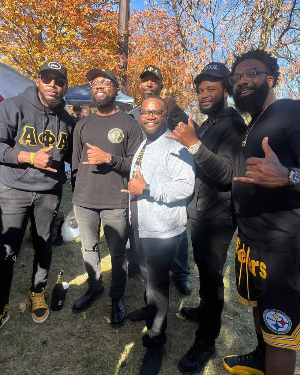A group of alumni pose for a photo at the tailgate before the football game.